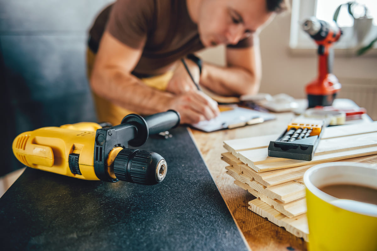 Homme qui écrit sur un calepin sur une table de travail.